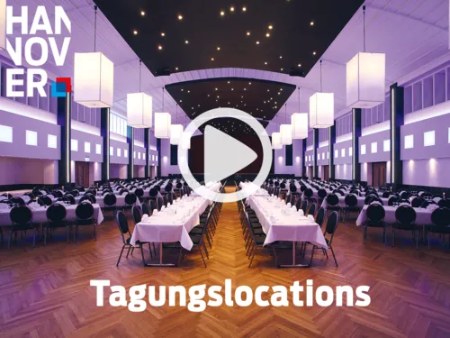 Gro&szlig;er, elegant beleuchteter Tagungssaal mit langen, festlich gedeckten Tischen und moderner Deckenbeleuchtung.